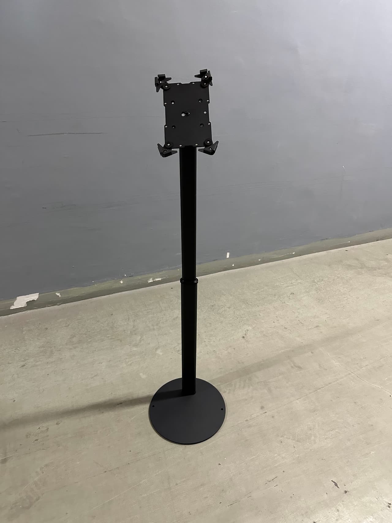 Black iPad floor stand with a round weighted base