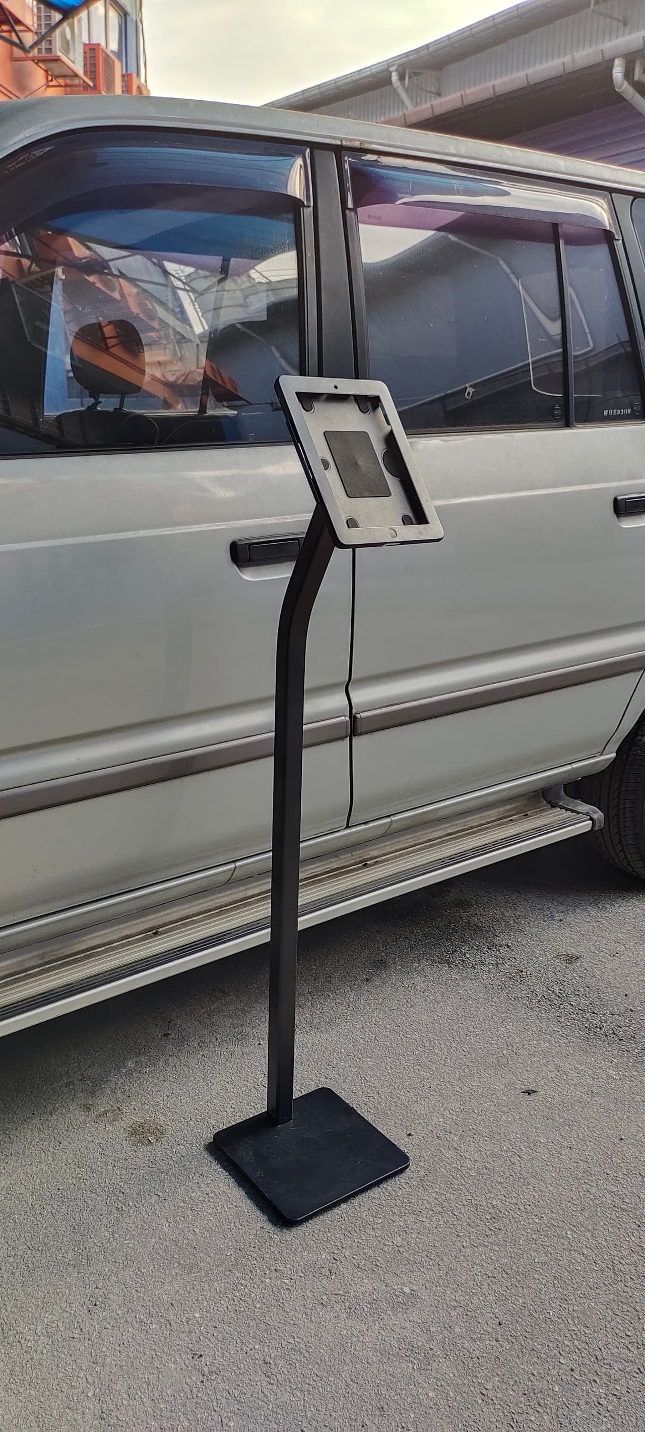 iPad floor stand positioned beside a vehicle at a showroom display