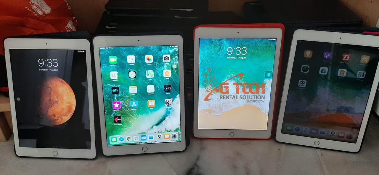 Four iPads laid out side by side, powered on and ready for testing